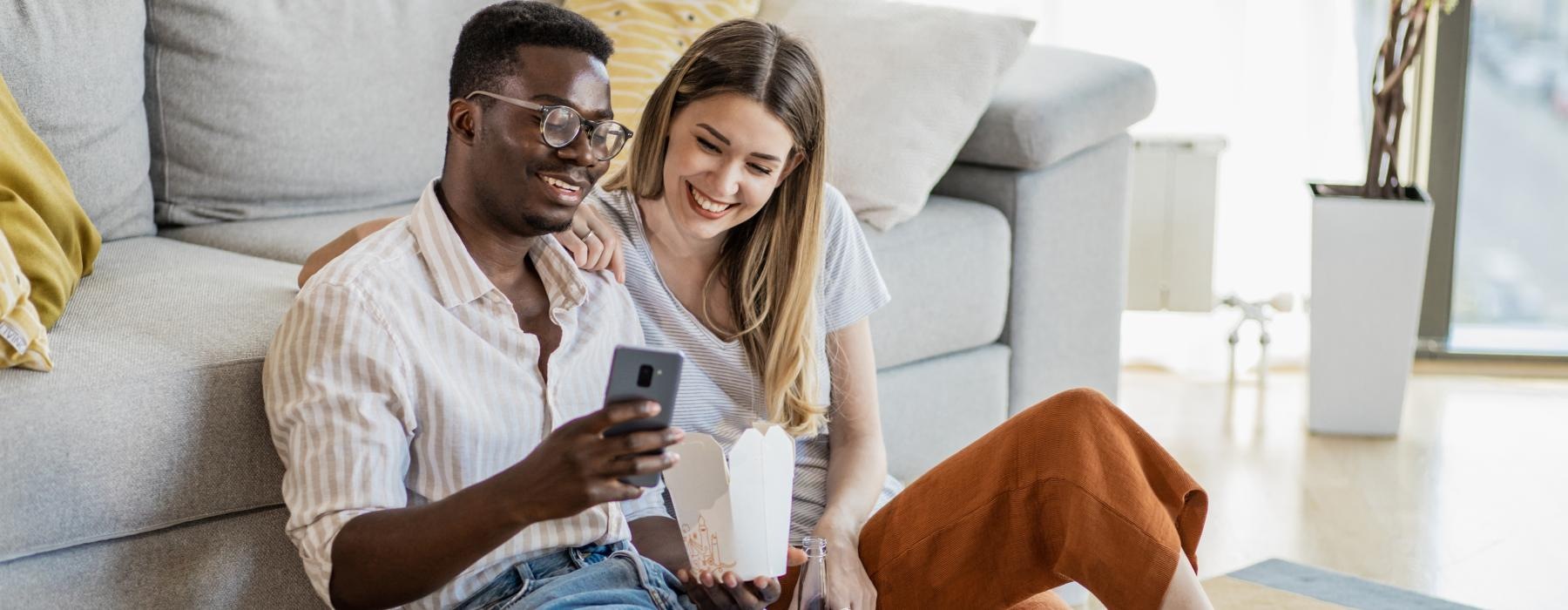 a man and a woman sitting on a couch and looking at a cell phone