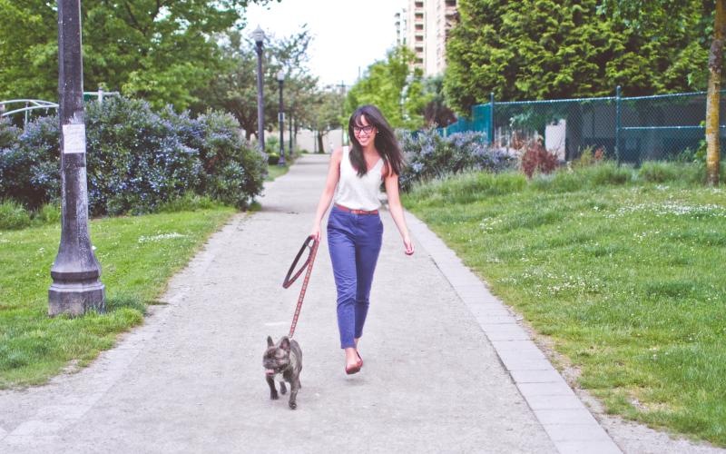 a woman walking a dog on a sidewalk